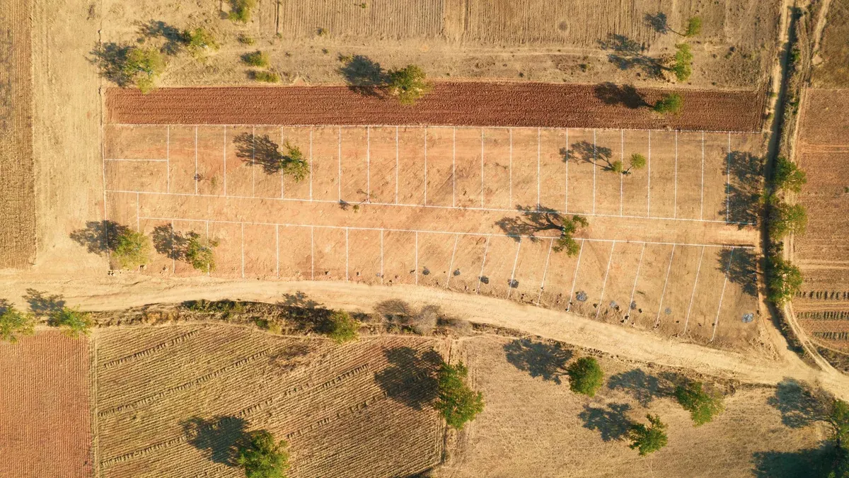 Drone shot of a rural farm landscape with fields and trees in summer.