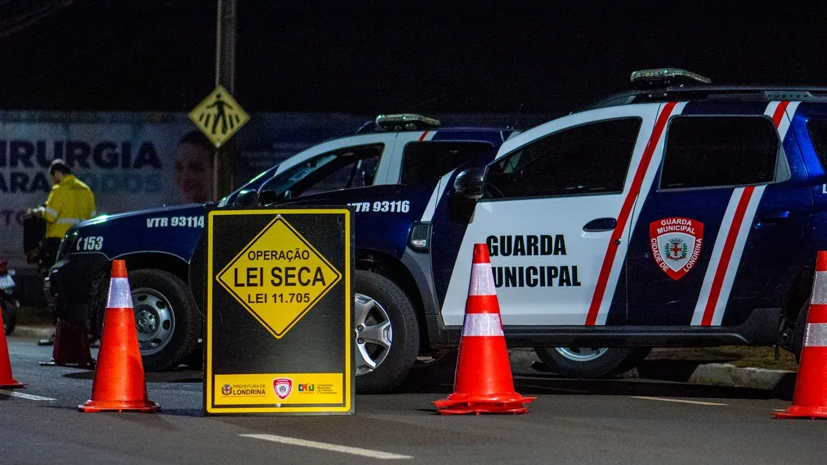 Night scene of a traffic checkpoint by the Municipal Guard in Londrina, Brasil, featuring police vehicles and cones.
