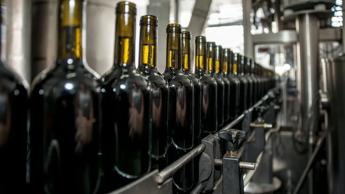 Rows of wine bottles on a production line in an industrial setting.