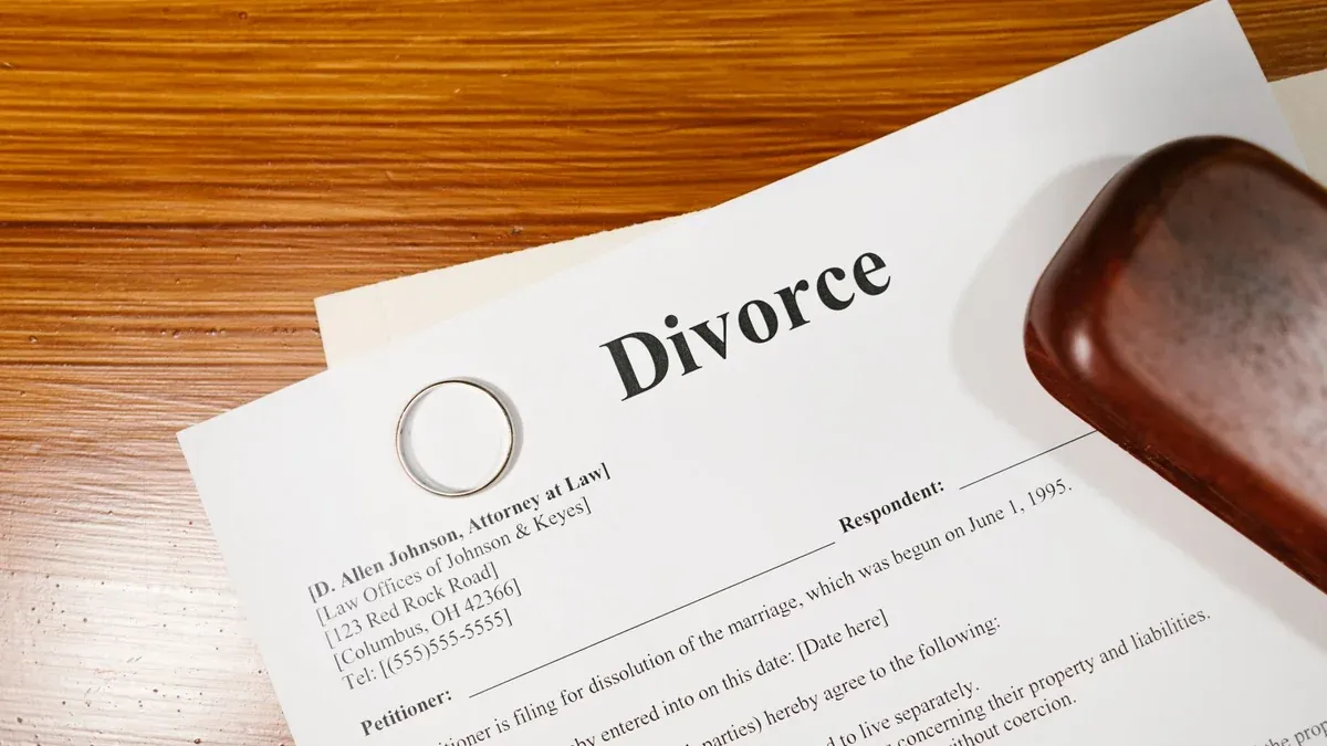 Close-up of a divorce document and wedding ring on a lawyer's desk.