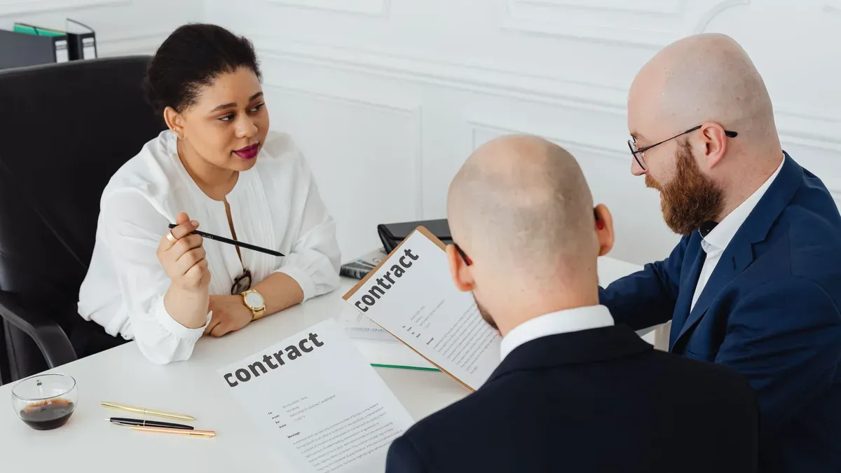 Three business professionals in discussion over a contract in a modern office setting.