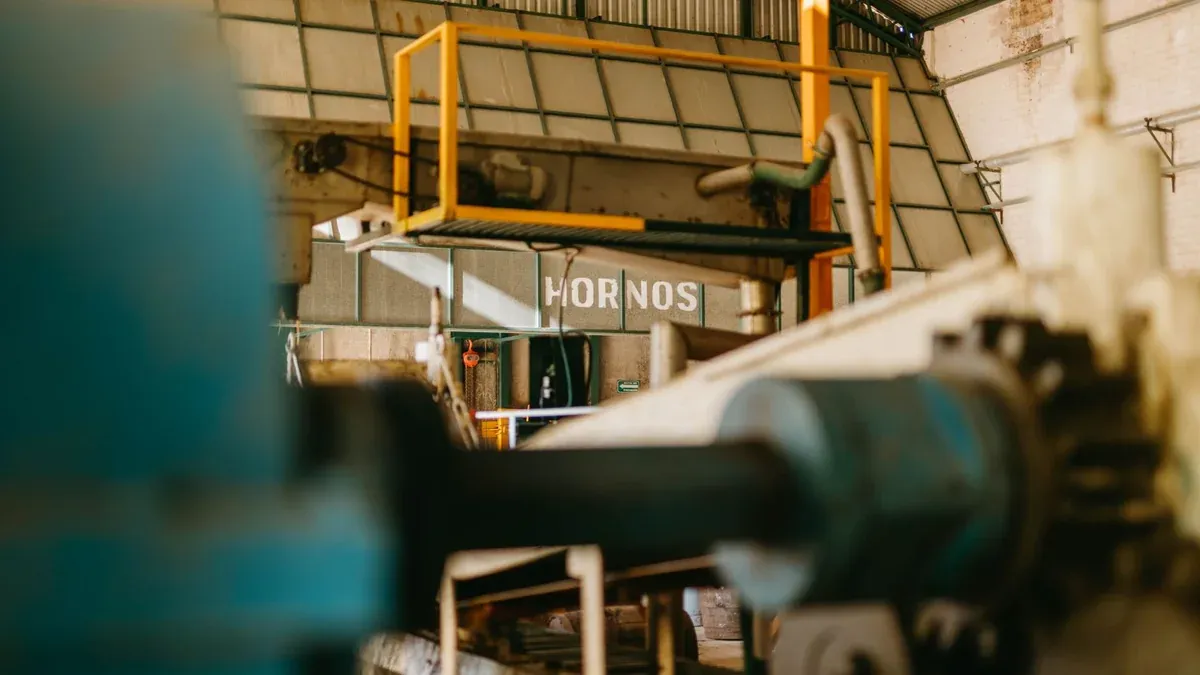 Close-up of heavy machinery inside an industrial factory with focus on ironworks and conveyor systems.