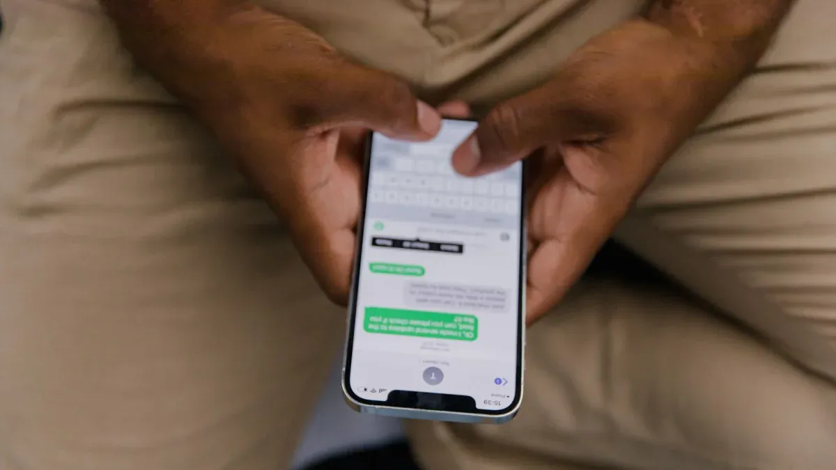 Close-up view of hands texting on a smartphone, focusing on the screen displaying messages.