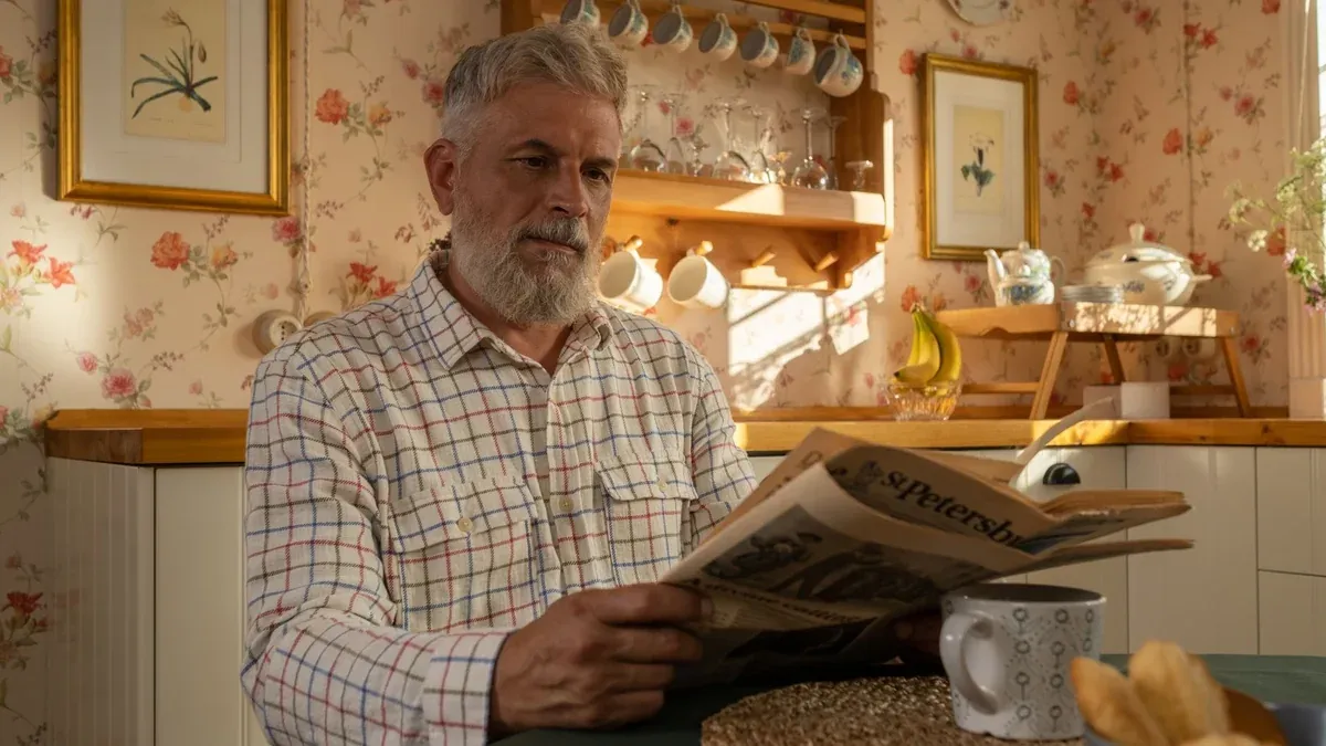Senior man enjoying morning newspaper in a warm, floral-themed kitchen