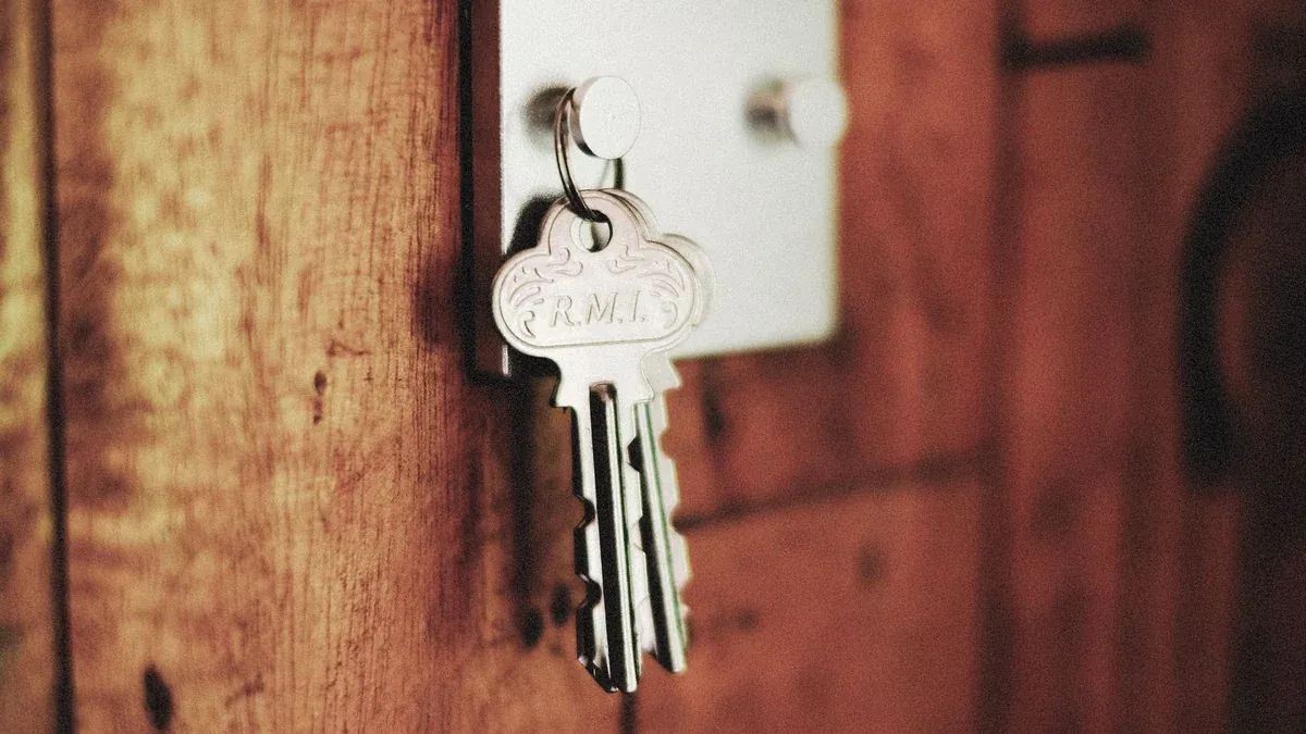 Detailed shot of keys hanging in a door lock on a wooden surface, warm tones.