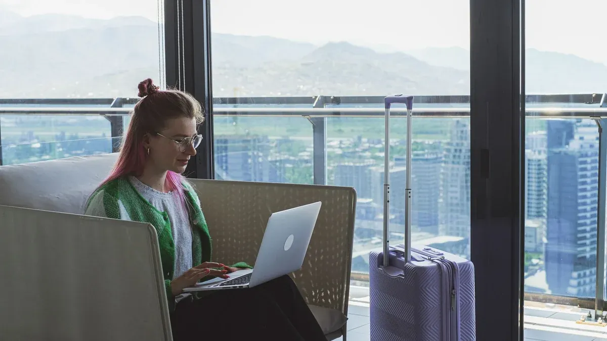 Woman working on a laptop in a hotel lounge with a stunning city view.