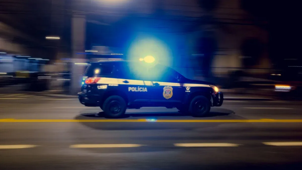 Blurred motion capture of a police car speeding at night with flashing lights on a city street.