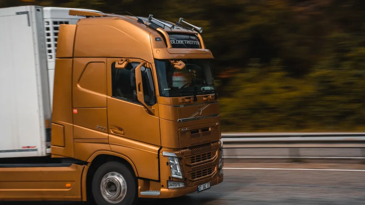 Orange truck speeding along a highway in Kemer, showcasing transportation and logistics.