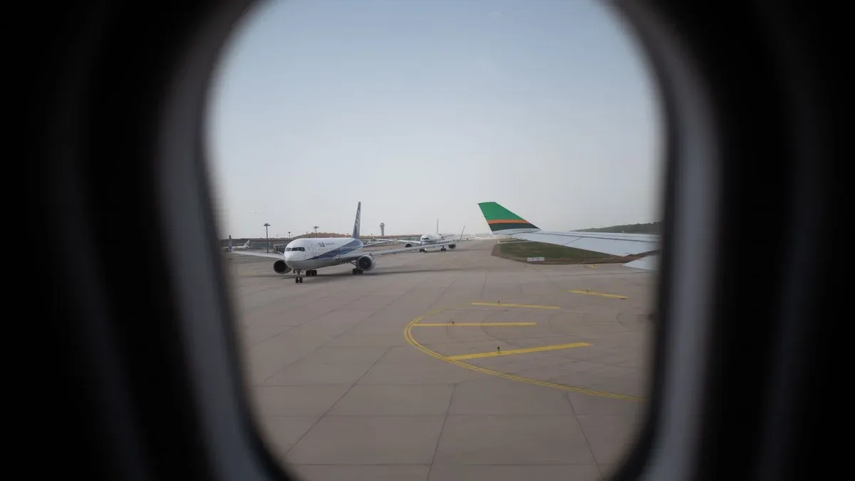 Airplane seen through a window, parked on the airport runway, capturing a travel moment.