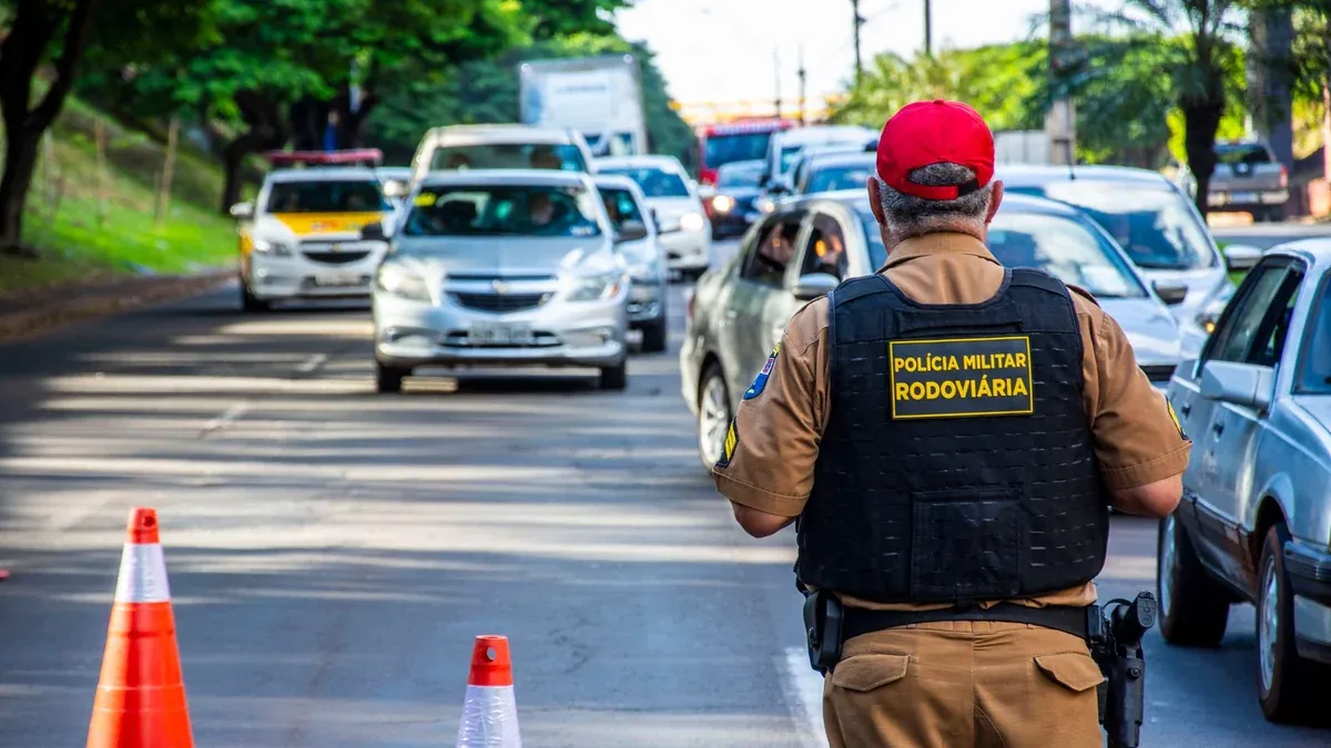 Police officer directing traffic in Londrina, Brazil with cars and cones on a busy street.