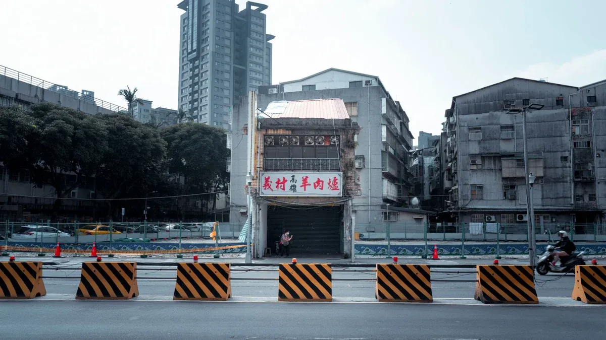 Cityscape featuring construction barriers, buildings, and urban street life.