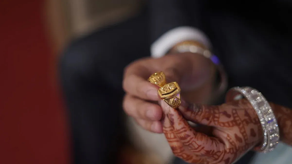 Close-up of hands with henna and gold rings, highlighting cultural wedding traditions.