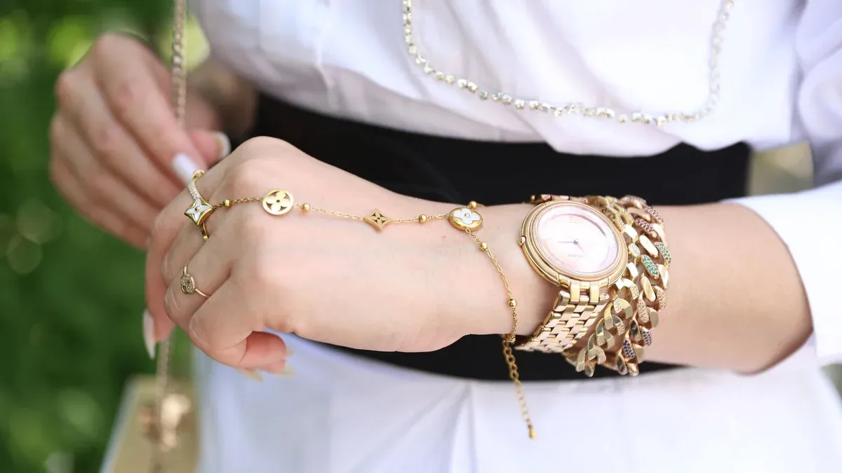 Close-up of a woman's wrist with elegant gold jewelry, showcasing style and luxury.