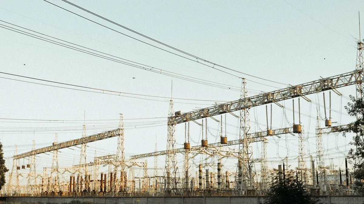 A wide view of an industrial electrical substation with power lines and towers outdoors.