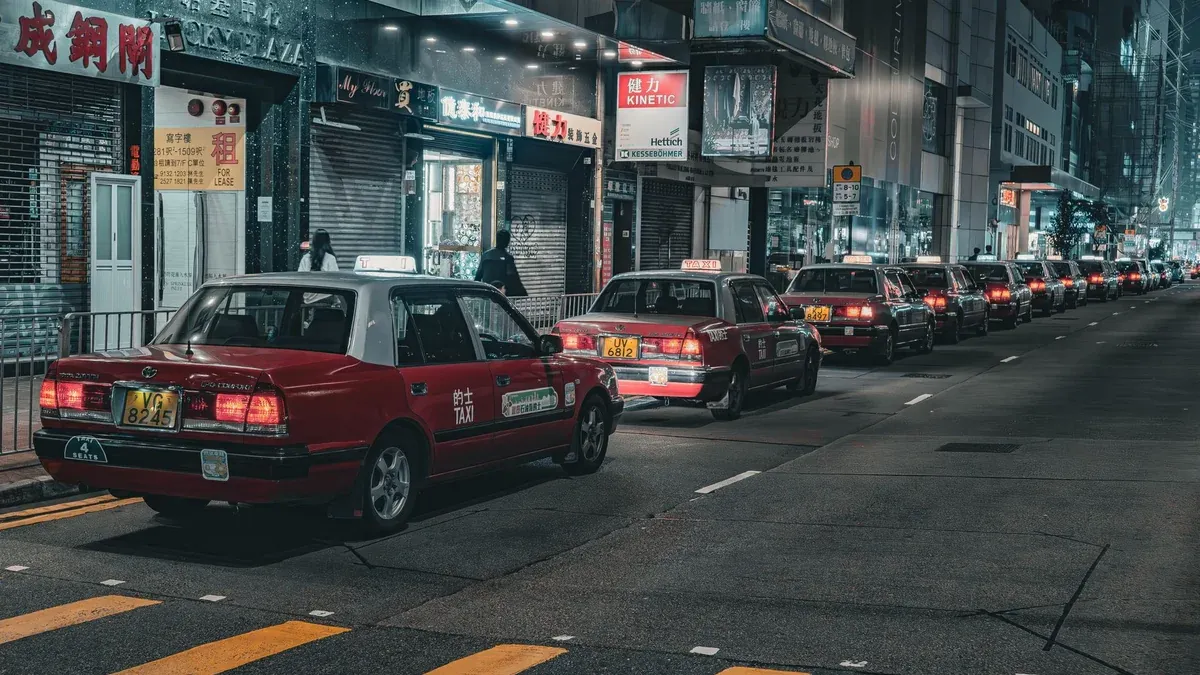 A street in Hong Kong bustling with red taxis at night, capturing urban life and city lights.