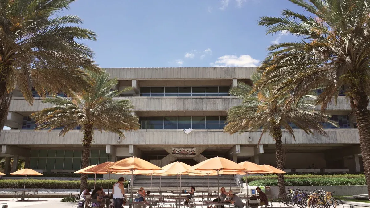 Outdoor scene of university campus life in Coral Gables, Florida featuring students studying under palm trees.
