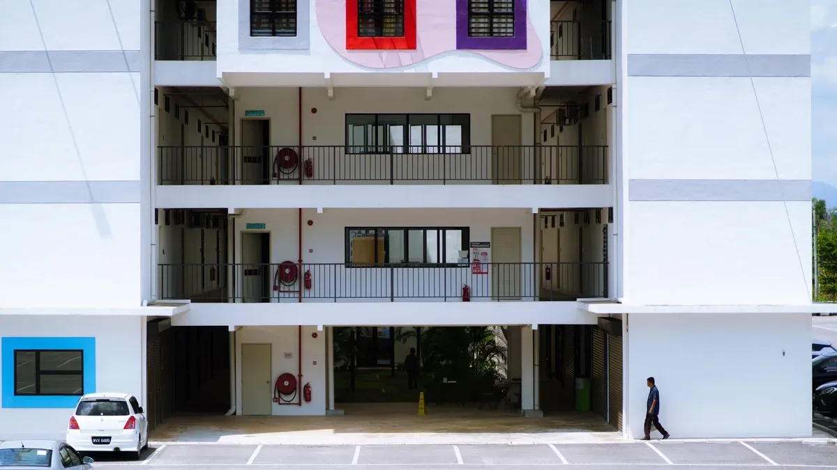Contemporary apartment building exterior with geometric wall art and empty parking lot.