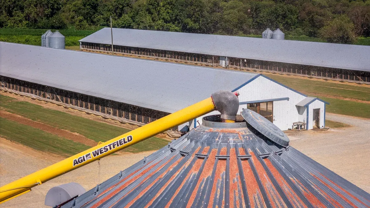 Aerial shot of a farm facility with grain silos and storage buildings on a sunny day.