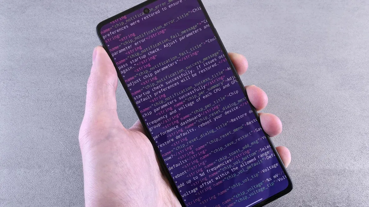 Close-up of a smartphone displaying code text held in a person's hand.