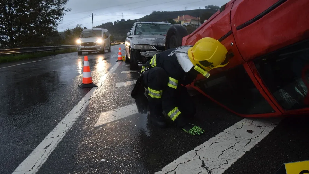 Firefighter attending to an overturned car on a rainy road in Póvoa de Lanhoso, Braga, Portugal.