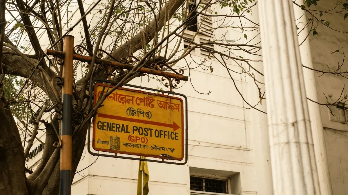 Historic General Post Office sign in Kolkata, India, with tree branches and colonial architecture.