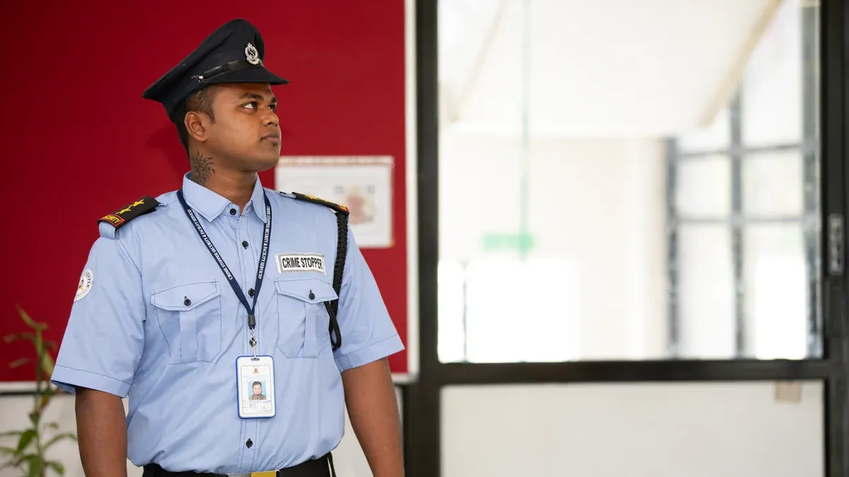 Security guard in uniform standing alert at a building entrance.