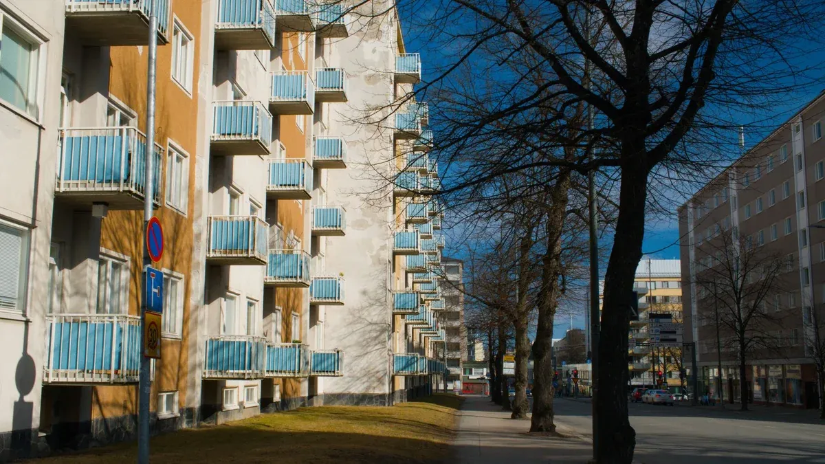 Cityscape featuring apartment buildings and trees along a street in Tampere, Finland.