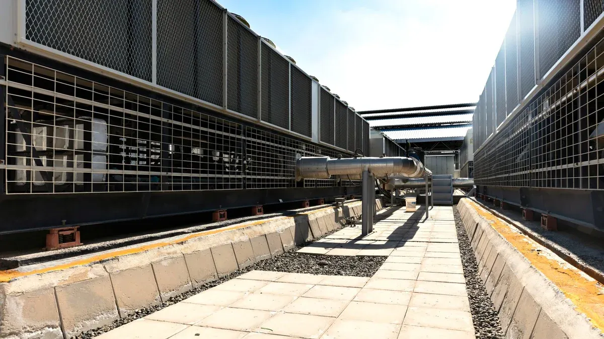 View of a large industrial cooling system with metal pipes and grids outdoors under bright daylight.