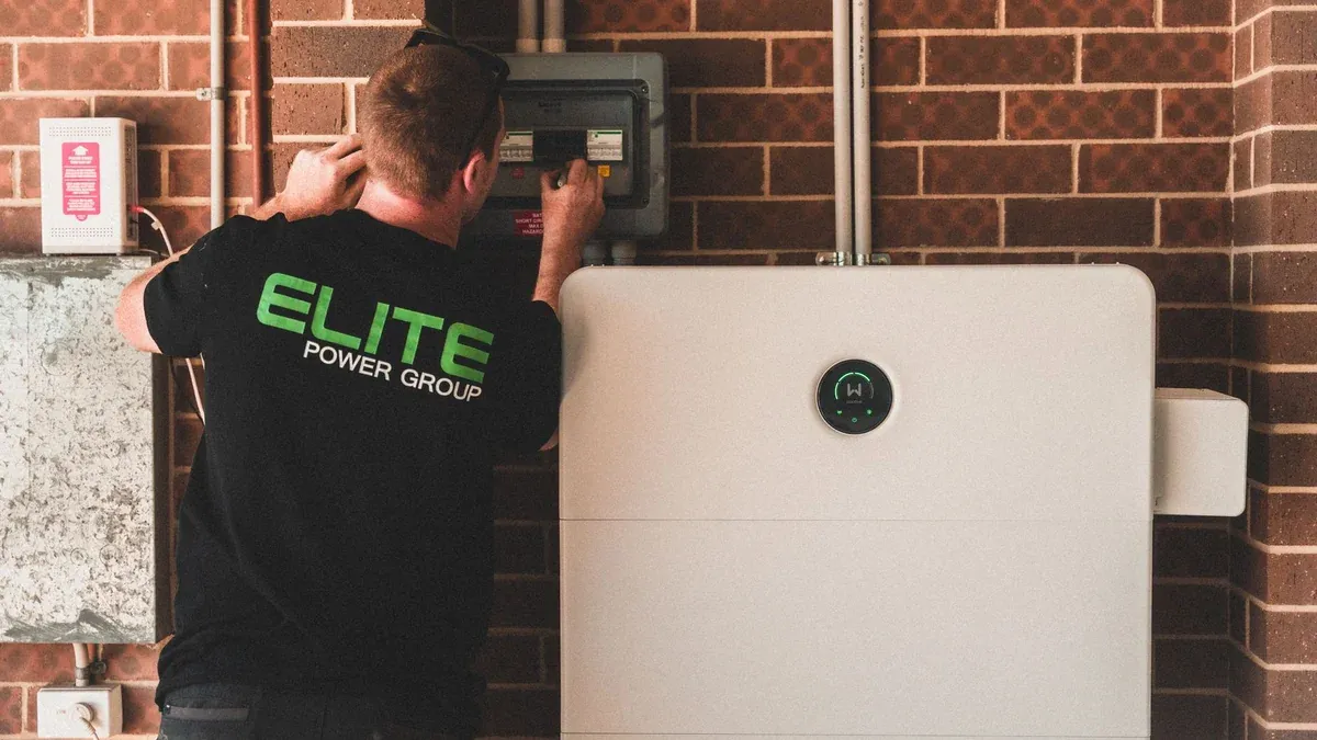 Electrician installing a home energy battery storage unit. Renewable and sustainable energy solution for residential use.