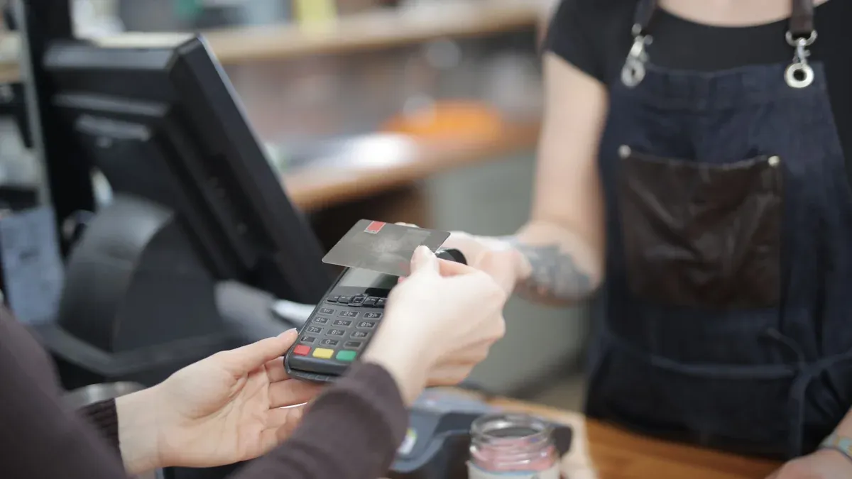 Close-up of customer and cashier during a credit card transaction at a store counter indoors.