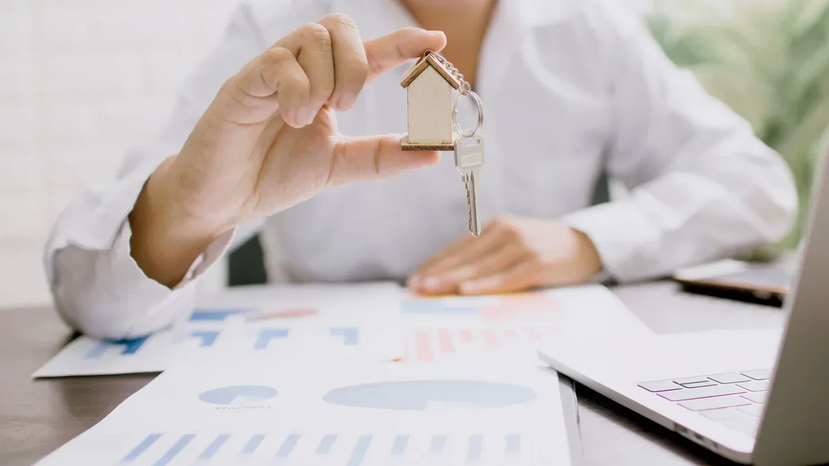 Real estate professional presenting a house model with keys, symbolizing property investment and ownership.