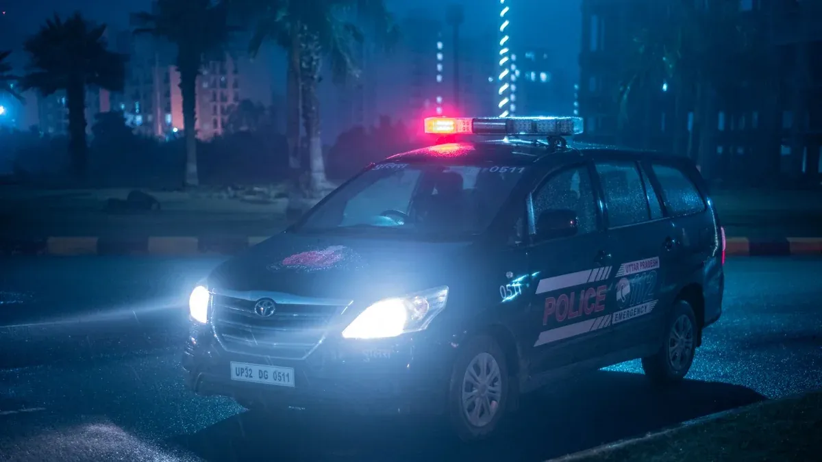 A Toyota police car patrols under city lights at night in Uttar Pradesh, India.