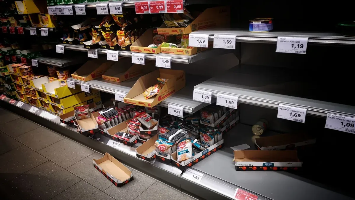 High angle of empty and full shelves in supermarket with price tags and cardboard boxes