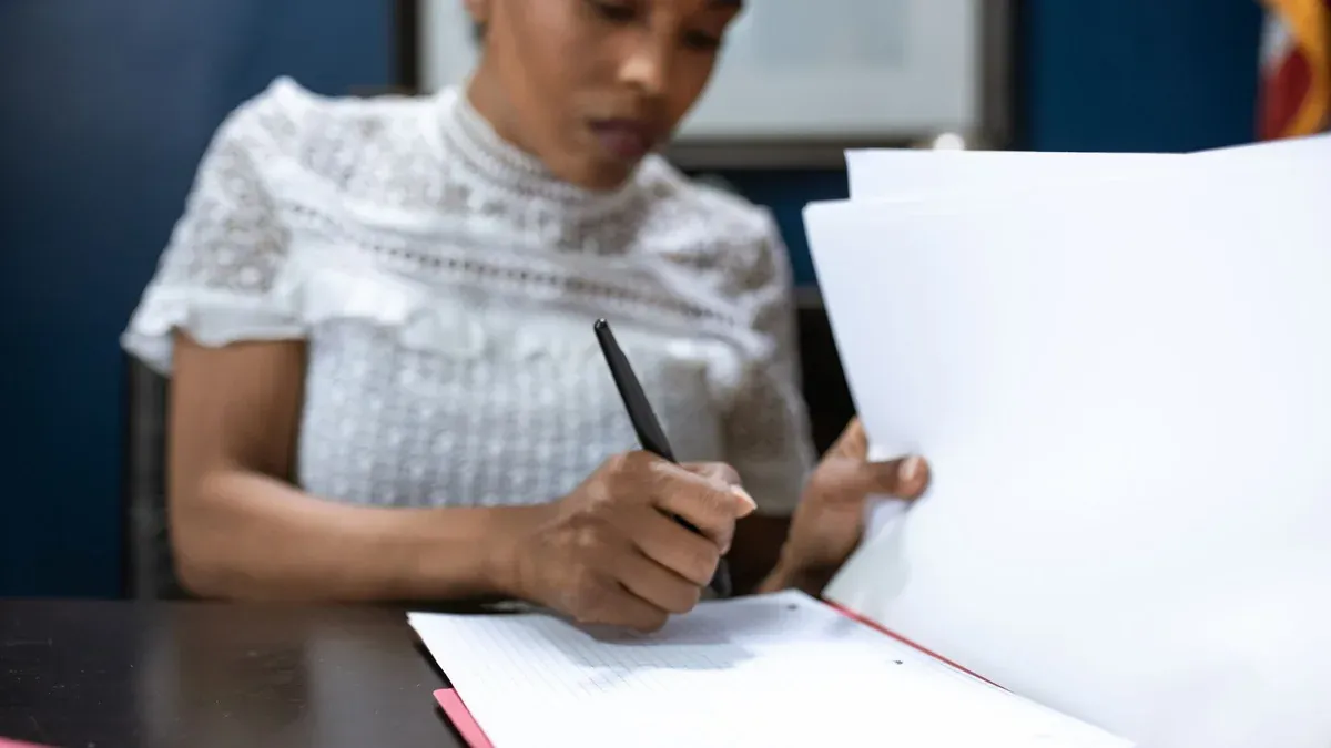 African American woman signing documents in an elegant office setting, showcasing leadership.