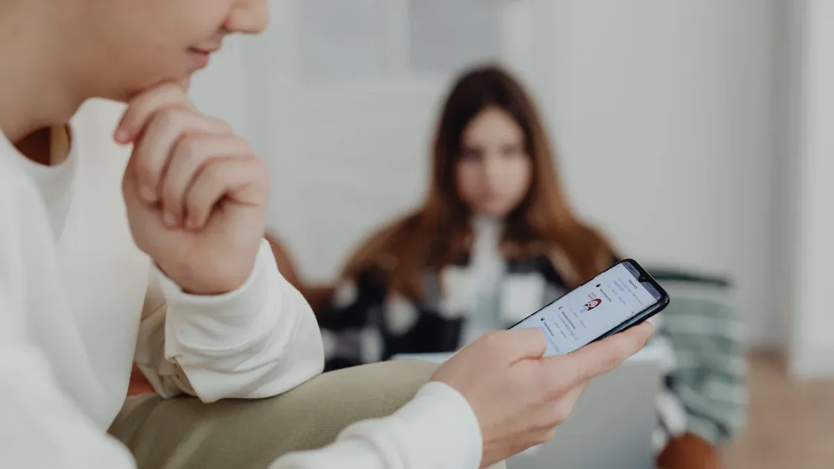 Teens using smartphones indoors with a blurred background, suggesting social media engagement.