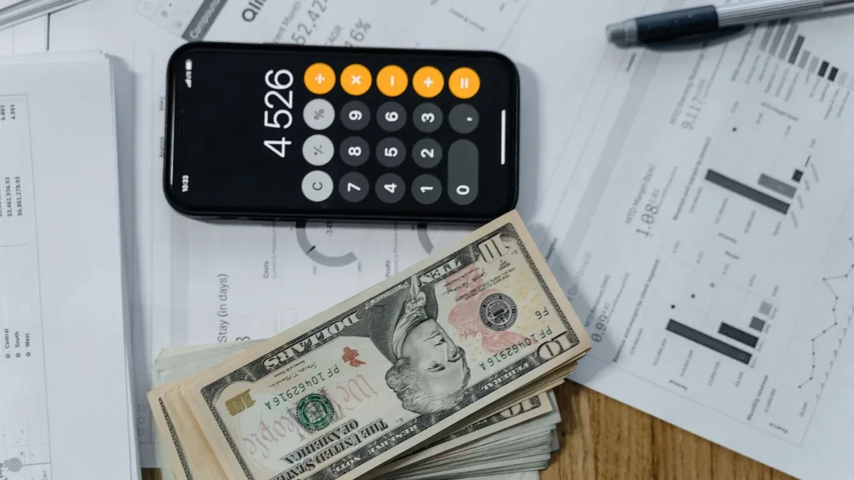 Mobile calculator, cash, and financial documents on a desk, indicating business planning.