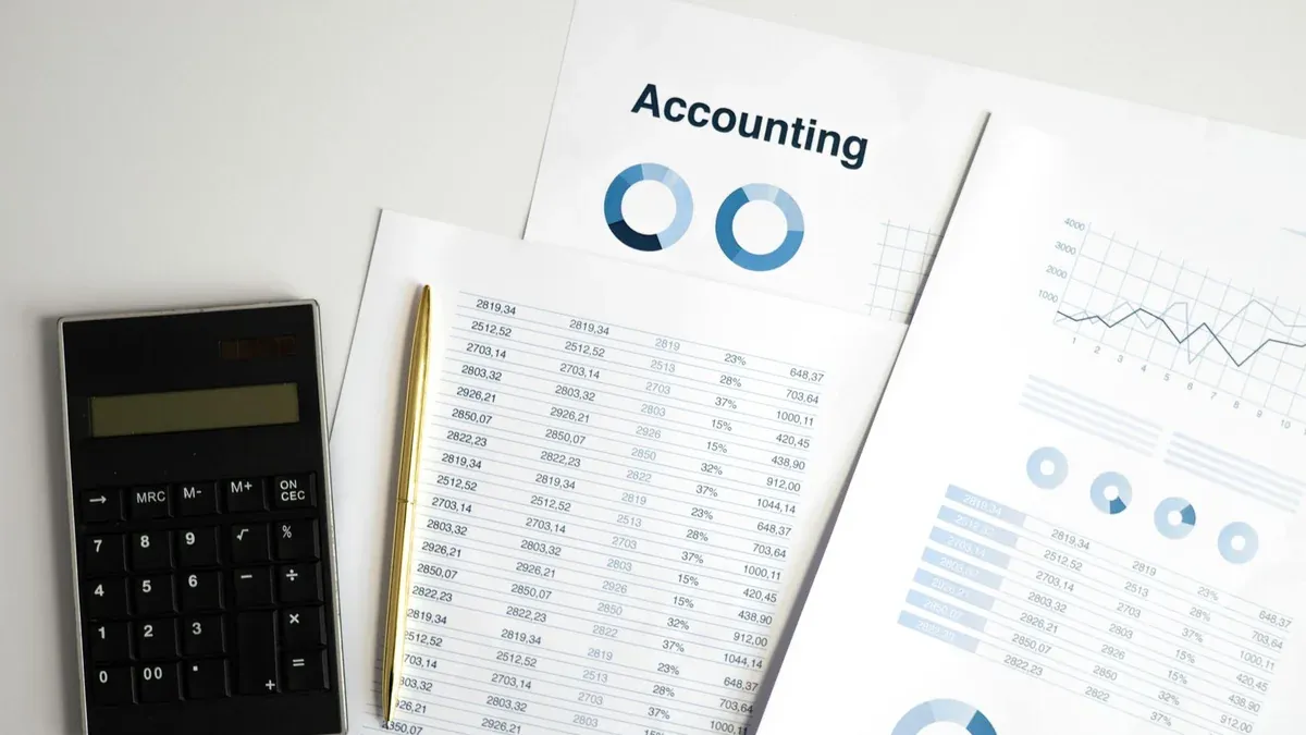 Calculator and accounting documents with charts on a workspace.
