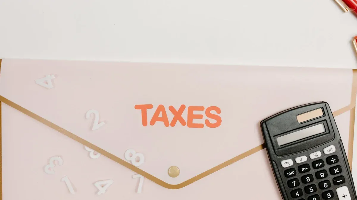 Flat lay of a calculator and folder labeled 'Taxes' for finance and accounting.