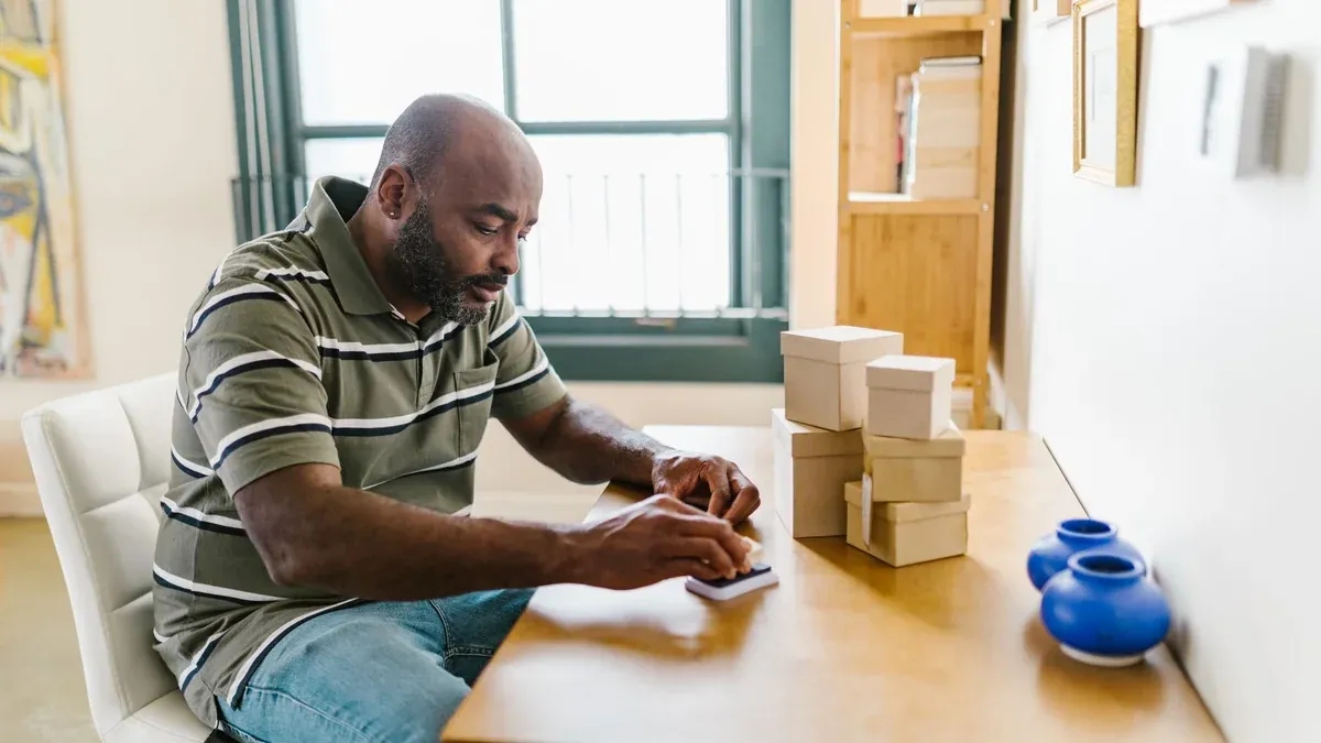 Bearded man in home office preparing packages for a small business startup.