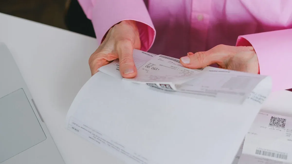 Business person handling paper receipts, meticulously organized.