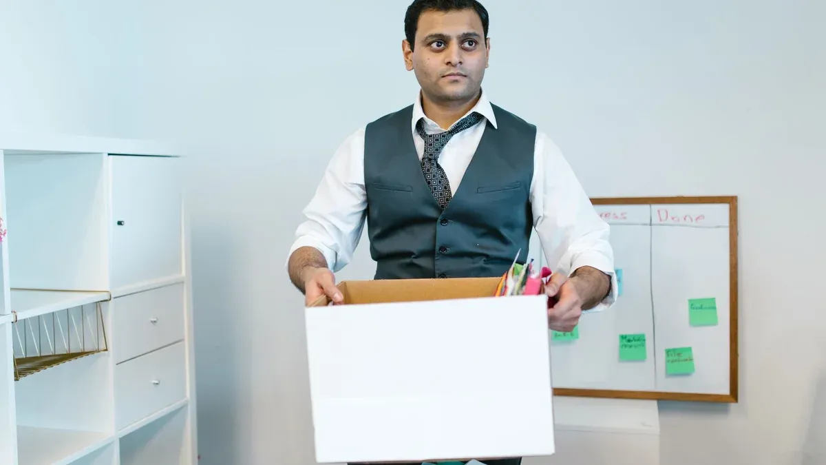 Professional man organizing office belongings in a cardboard box, preparing for transition.