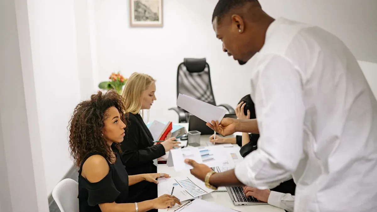 An office meeting where a man argues with a woman over documents, causing tension.