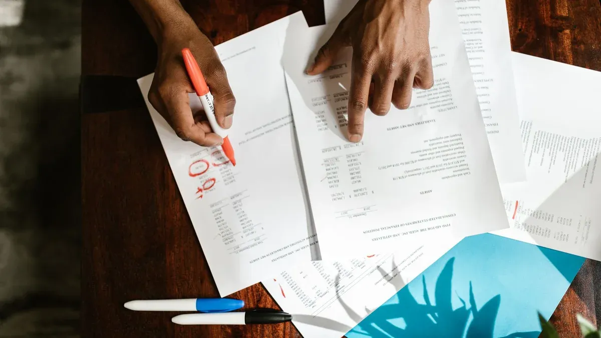 Overhead view of hands highlighting financial documents on a desk.