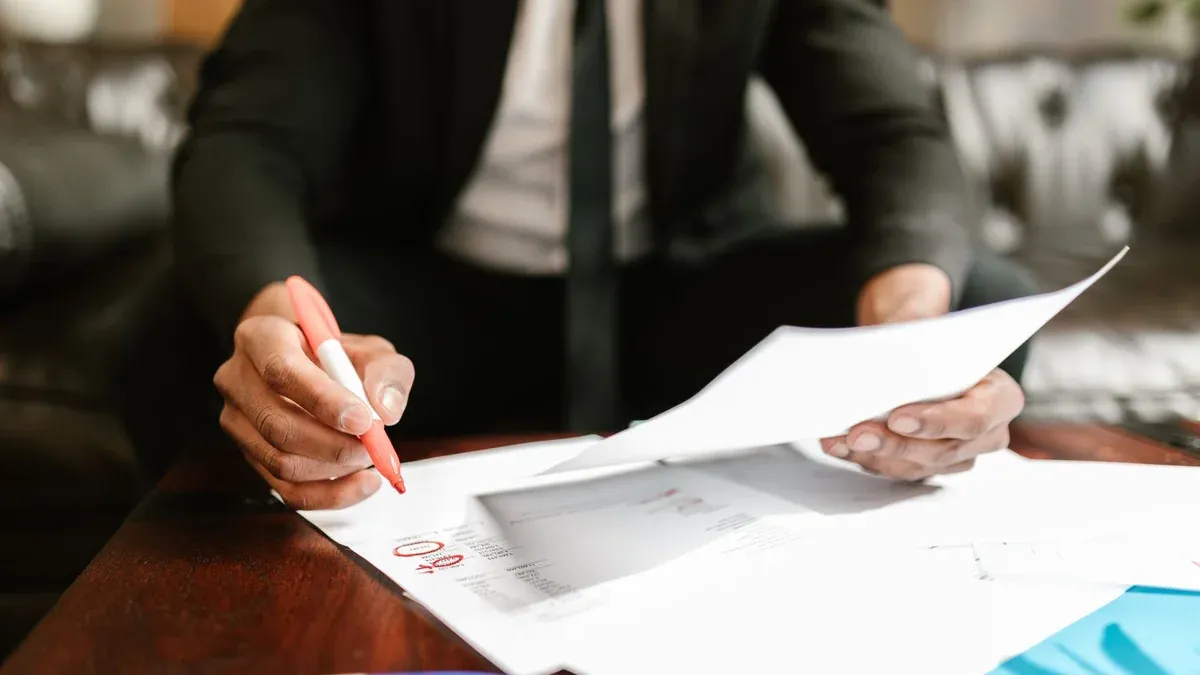 Businessman working with financial documents at office desk, highlighting details.