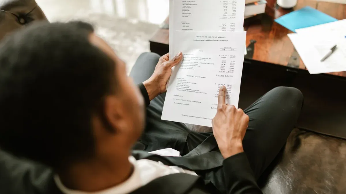 Business professional examining financial documents, focusing on analytics and paperwork in an office setting.