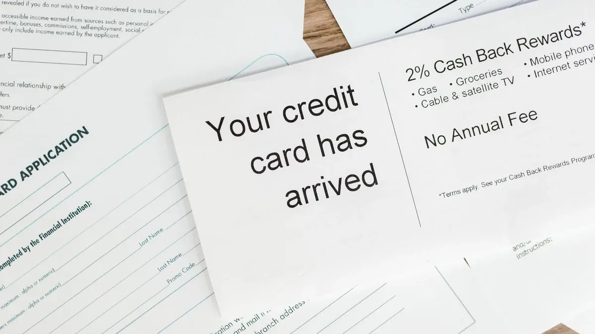 Close-up of a letter announcing the arrival of a credit card amidst financial documents.