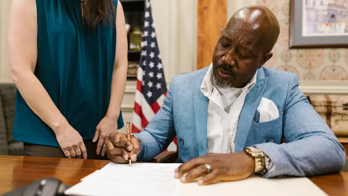 Professional lawyer signing documents in an elegant law office setting, showcasing a serious work environment.