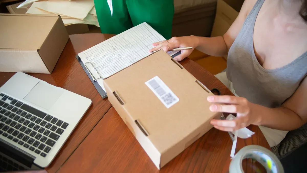 Two people packing online orders in a small business setting with a laptop.