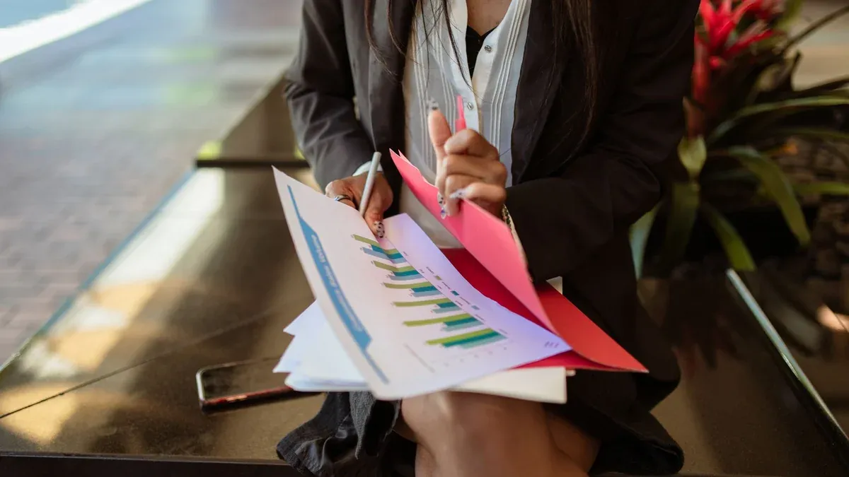 A woman in a blazer sits outside reviewing sales documents, highlighting analysis.