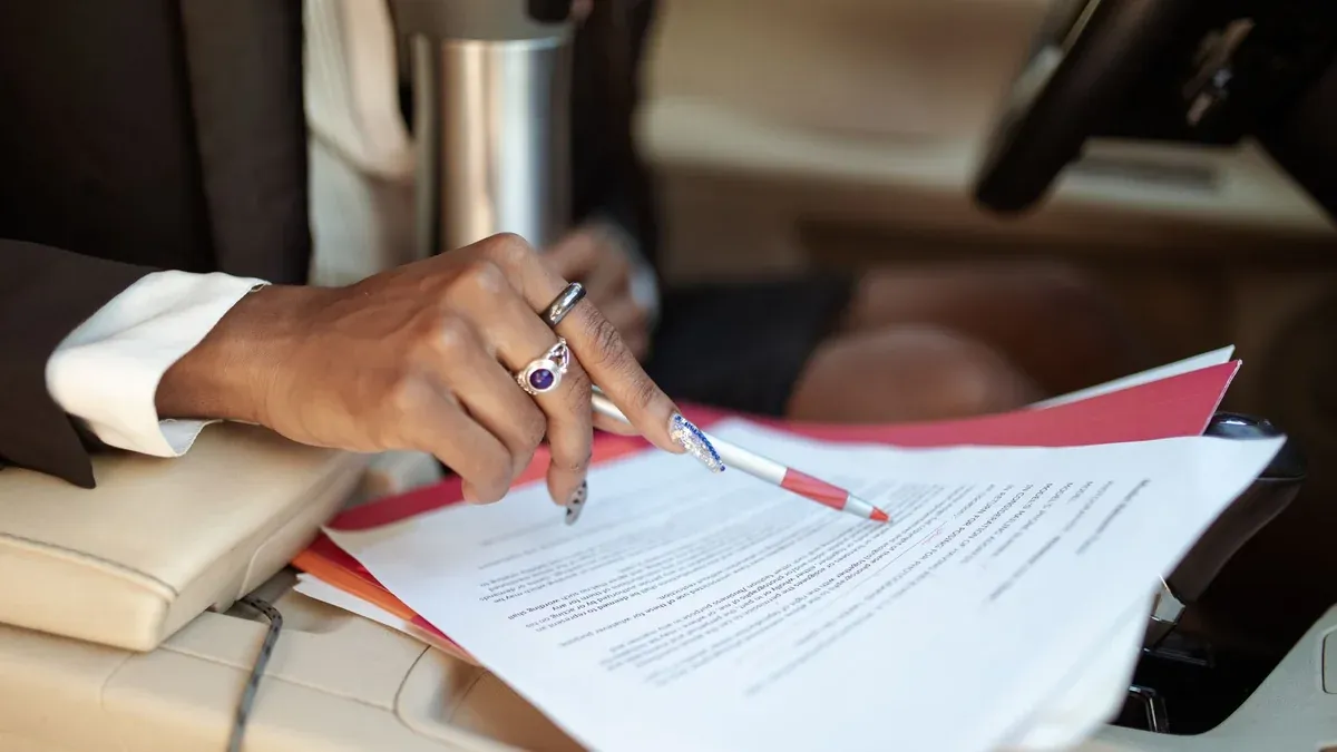 A professional reviewing documents in a car interior, focusing on hand and paperwork.